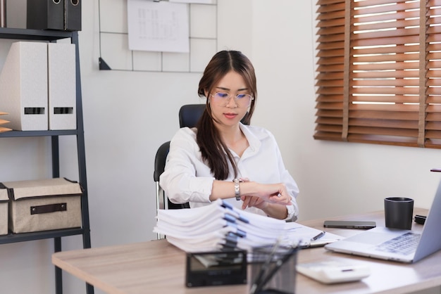 Geschäftskonzept Geschäftsfrau sieht sich die Zeit auf der Armbanduhr an, nachdem sie hart im Büro gearbeitet hat