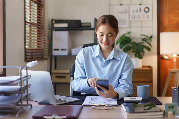 Geschäftskonzept: Geschäftsfrauen prüfen und lesen Finanzdaten auf dem Smartphone am Arbeitsplatz