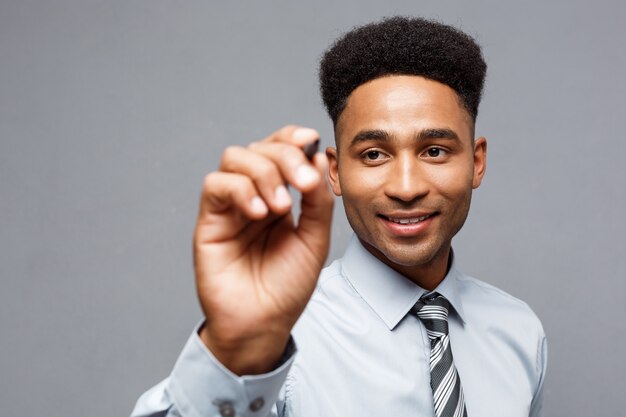 Geschäftskonzept - Selbstbewusster afroamerikanischer Geschäftsmanager, der bereit ist, im Büro auf eine virtuelle Tafel oder ein Glas zu schreiben.