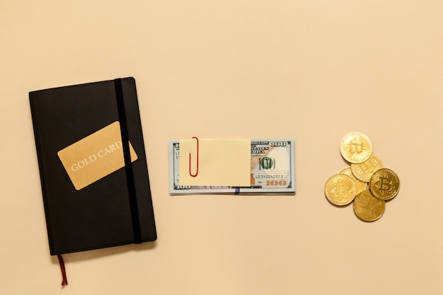 Geschäftskonzeptartikel auf dem Tisch Gold-Bitcoins-Dollar-Tagebuch-Goldkarte auf beigem Hintergrund