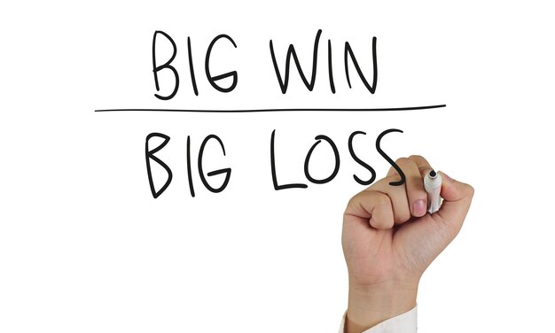 Foto geschäftskonzeptbild einer hand, die einen marker hält und big win oder big loss isoliert auf weiß schreibt