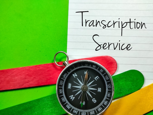 GeschäftskonzeptText-Transkriptionsdienst schreiben auf Briefpapier mit Kompass und farbigen Eiscreme-Sticks auf grünem Hintergrund
