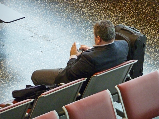 Geschäftsleute, die allein auf ihren Flug warten und mit ihrem Pocket-PC arbeiten