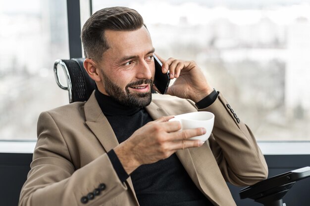 Foto geschäftsleute, die am handy mit einer kaffeetasse in ihren händen sprechen