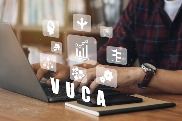 Foto geschäftsleute, die einen computer zu vuca-text verwenden, umgeben von symbolen für volatilität, unsicherheit, komplexität, mehrdeutigkeit, hintergrund kopieren