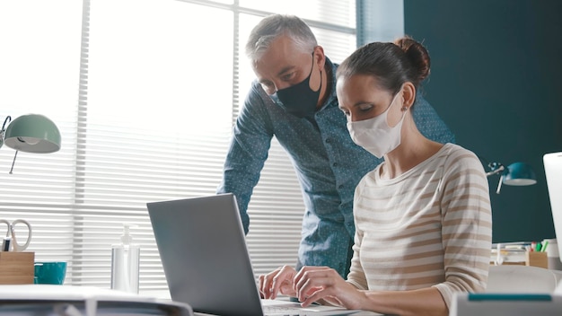 Geschäftsleute, die im Büro zusammenarbeiten und Gesichtsmasken tragen