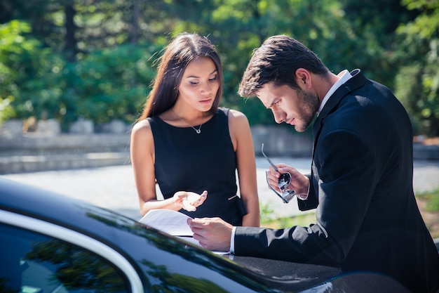 Geschäftsleute, die im Freien Dokumente in der Nähe von Auto lesen