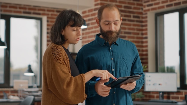 Geschäftsleute, die Informationen auf digitalen Tablets analysieren, um Projekt- und Tarifdiagramme zu planen. Mann und Frau arbeiten mit Geräten zusammen, um Marketingstrategien und Präsentationen im Büro zu entwerfen.