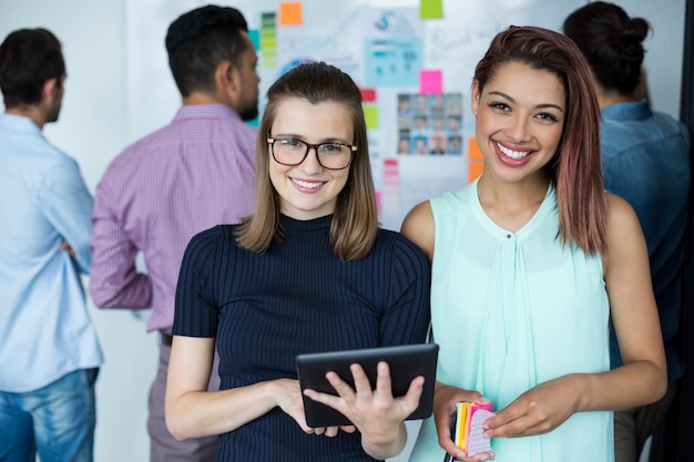 Geschäftsleute, die mit digitalem Tablett und Kaffeetasse im Büro stehen