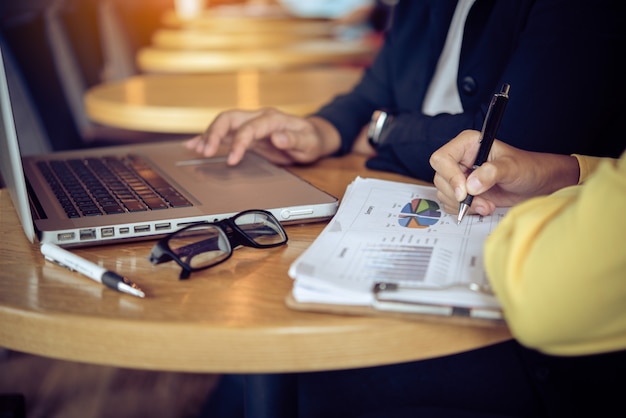 Geschäftsleute, die mit Laptop und Smartphone im offenen Raumbüro arbeiten. Sitzungsbericht in Bearbeitung