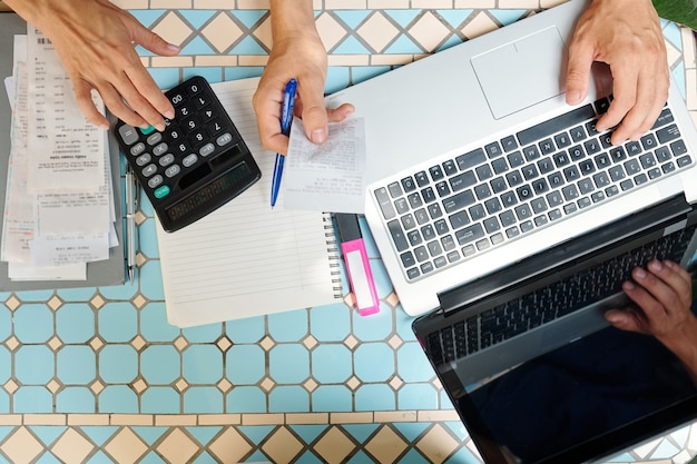 Geschäftsleute, die Rechnungen online über die Website auf dem Laptop bezahlen und Ausgaben berechnen, Ansicht von oben