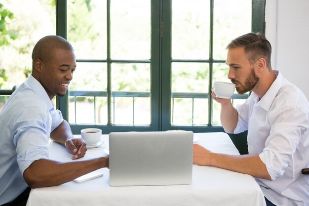 Geschäftsleute, die über Laptop am Tisch im Restaurant diskutieren