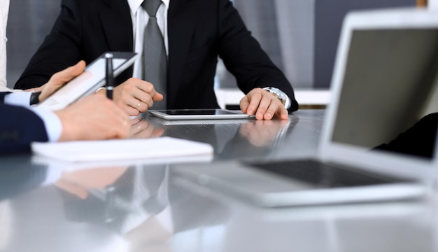 Geschäftsleute diskutieren Verträge über die Zusammenarbeit bei einem Treffen am Glasschreibtisch im modernen Büro