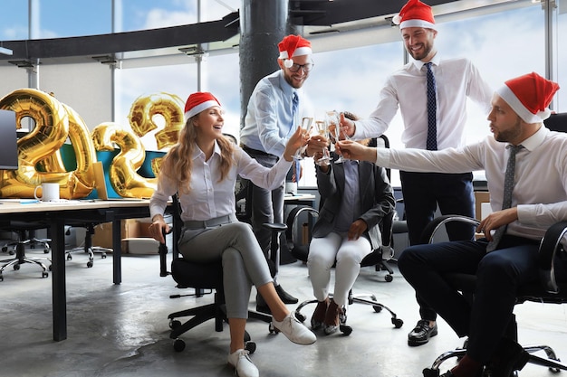 Geschäftsleute feiern Feiertage im modernen Büro, trinken Champagner und haben Spaß beim Coworking Frohe Weihnachten und ein gutes neues Jahr 2023