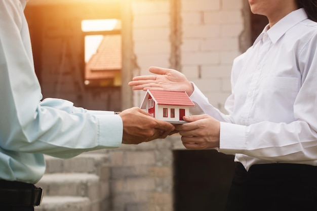 Geschäftsleute geben sich die Hand und stimmen zu, Häuser zu kaufen und zu verkaufen