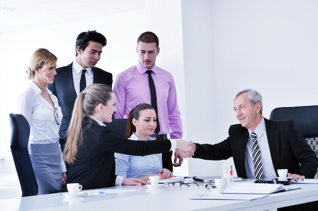 Geschäftsleute gruppieren sich bei einem Meeting in einer hellen und modernen Büroumgebung.