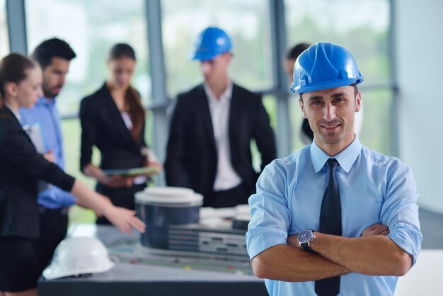 Foto geschäftsleute gruppieren sich zu treffen und präsentationen in einem hellen, modernen büro mit bauingenieur, architekt und arbeiter, der gebäudemodell und baupläne plant