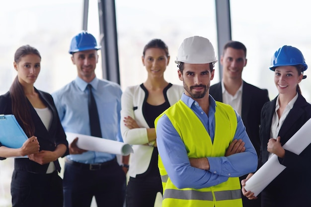 geschäftsleute gruppieren sich zu treffen und präsentationen in einem hellen, modernen büro mit bauingenieur, architekt und arbeiter, der gebäudemodell und baupläne plant