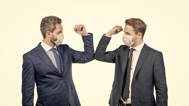 Geschäftsleute in Schutzmaske stoßen Ellbogen an, anstatt Hände zu schütteln, um Kontakt zu vermeiden, während Covid19-Coronavirus-Pandemie-Geschäftsbegrüßung