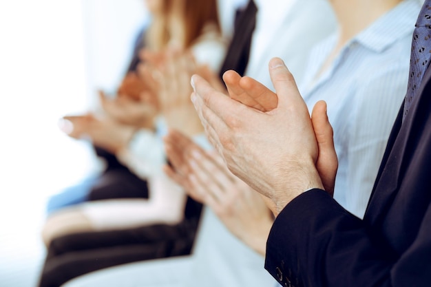 Geschäftsleute klatschen und applaudieren bei Meetings oder Konferenzen, Nahaufnahme der Hände. Gruppe unbekannter Geschäftsmänner und -frauen im modernen weißen Büro. Erfolg Teamwork oder Corporate Coaching-Konzept.