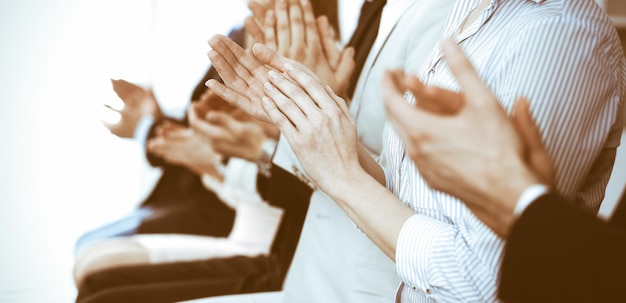 Geschäftsleute klatschen und applaudieren bei Meetings oder Konferenzen, Nahaufnahme der Hände. Gruppe unbekannter Geschäftsmänner und -frauen im modernen weißen Büro. Erfolg Teamwork oder Corporate Coaching-Konzept.