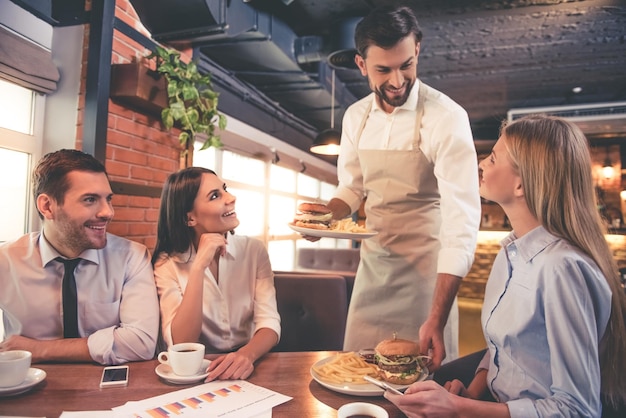 Geschäftsleute lächeln und bekommen ihre Bestellung beim Mittagessen im Café