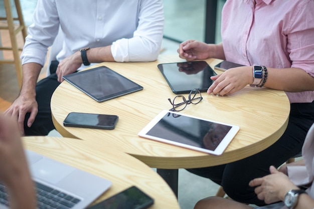 Geschäftsleute mit digitalen Tablets Smartphone und Laptop auf dem Tisch