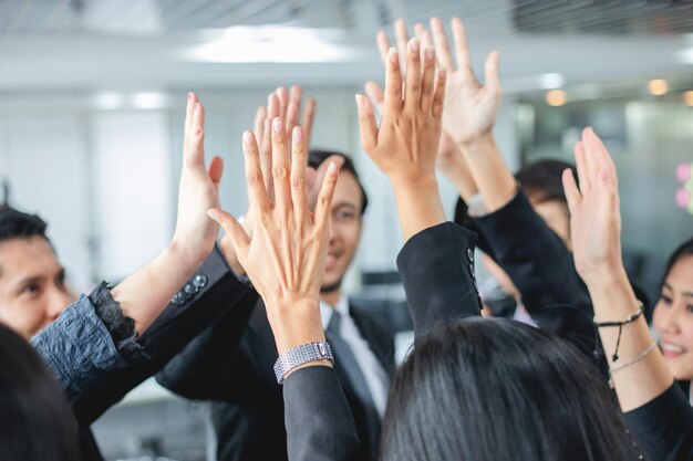 Foto geschäftsleute mit erhobenen armen stehen im büro