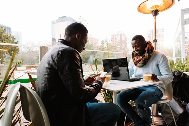 Geschäftsleute mit Handy und Laptop im Café. Geschäftskonzept