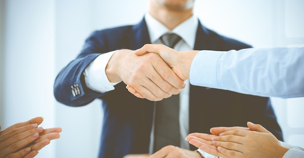 Geschäftsleute oder Anwälte, die sich die Hände schütteln und ein Meeting in einem blau getönten Büro beenden, Nahaufnahme. Erfolg bei Verhandlungs- und Handschlagkonzepten.