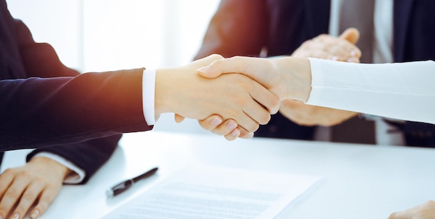Geschäftsleute oder Anwälte schütteln sich die Hände und beenden ein Treffen oder eine Verhandlung im sonnigen Büro. Geschäftlicher Händedruck und Partnerschaft.