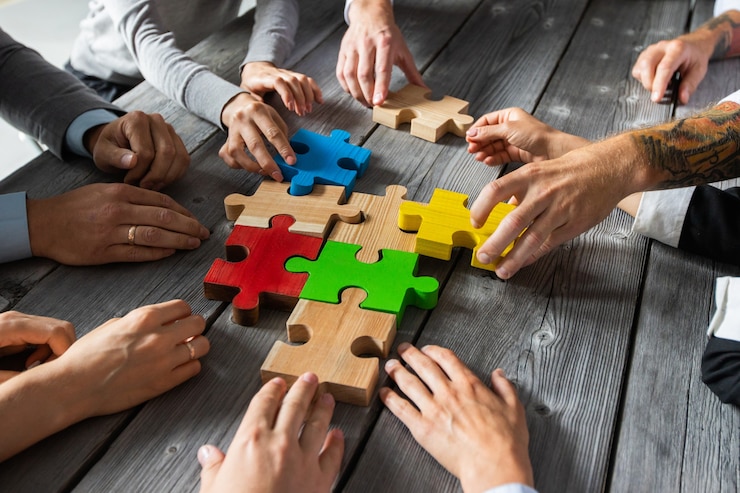 Foto geschäftsleute sitzen am besprechungstisch und montieren farbpuzzleteile einheitskonzept für kooperationsideen