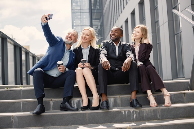 Geschäftsleute sitzen auf einer Treppe und machen ein Selfie