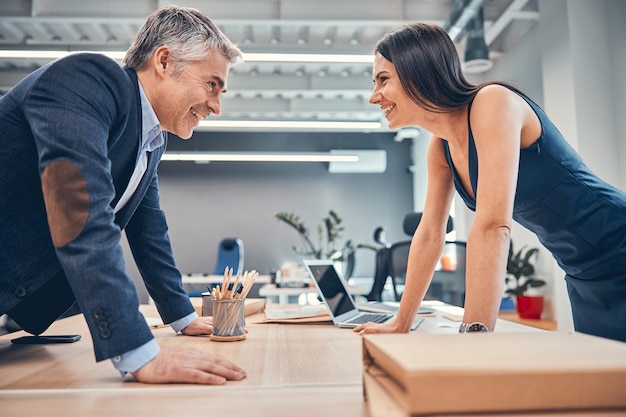 Geschäftsleute stehen sich im Besprechungsraum gegenüber und lachen bei der Arbeit