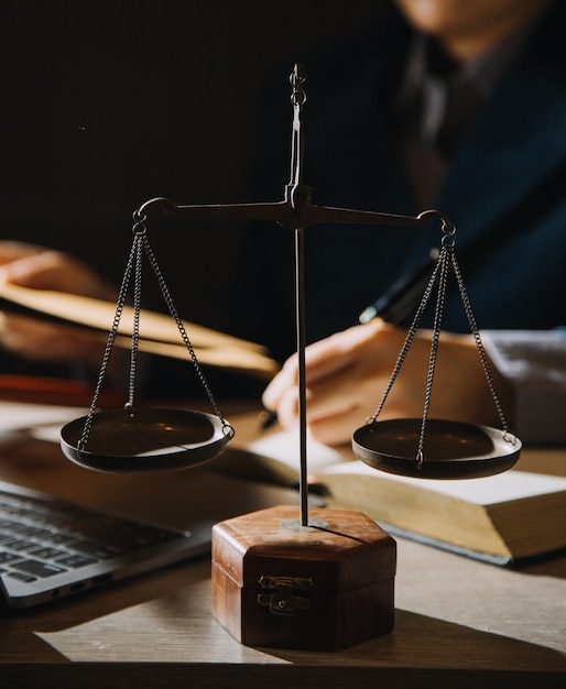 Geschäftsleute und Anwälte diskutieren Vertragspapiere mit Messingwaage auf dem Schreibtisch im Büro Rechtliche Dienstleistungen beraten Justiz- und Rechtskonzepte