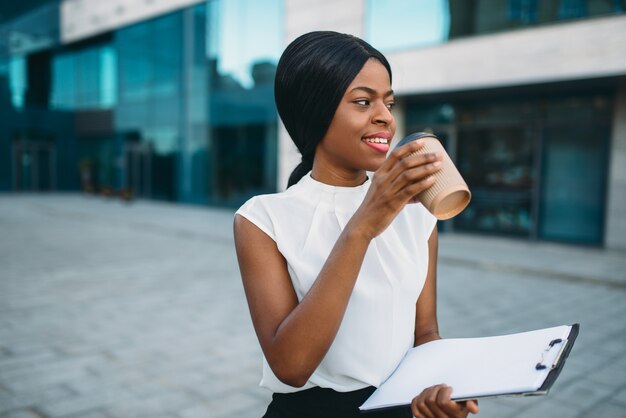 Geschäftsmädchen grinst kaffee aus pappbecher