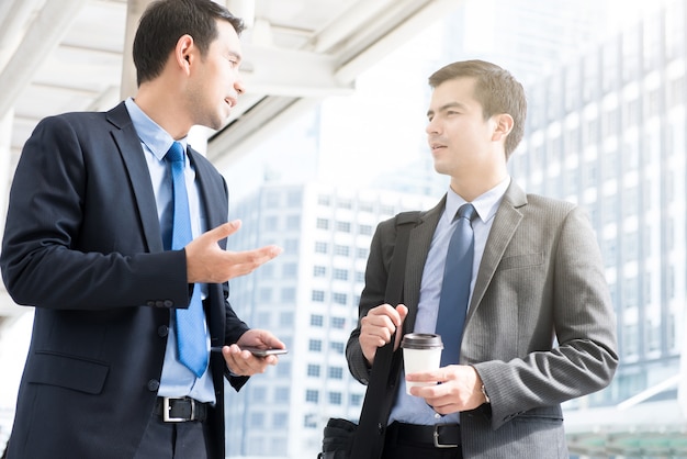 Geschäftsmänner, die beim Gehen sich besprechen, um morgens zu arbeiten