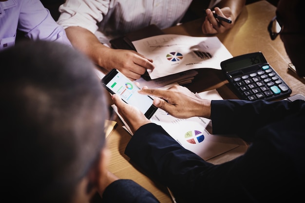 Geschäftsmänner, welche die Arbeit sitzt im Bürokonferenzsaal an der Nachtszene besprechen