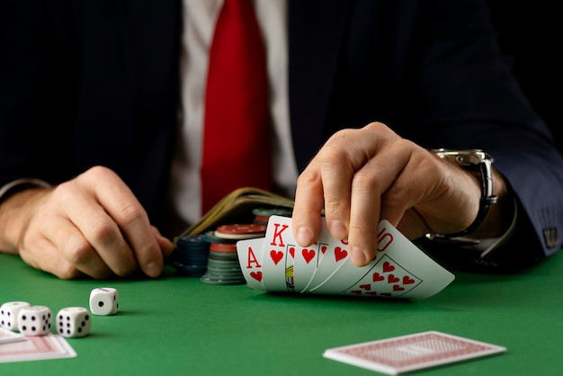 Geschäftsmann am grünen Spieltisch mit Spielchips, Karten und Würfeln, die Poker und Blackjack im Kasino spielen