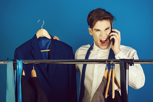 Geschäftsmann am Kleiderbügel mit Telefon, wütender Mann schreiend