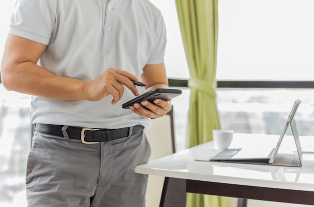 Geschäftsmann arbeitet am Handy mit Laptop auf dem Tisch