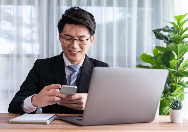 Geschäftsmann arbeitet am Schreibtisch am Laptop und telefoniert jubelnd