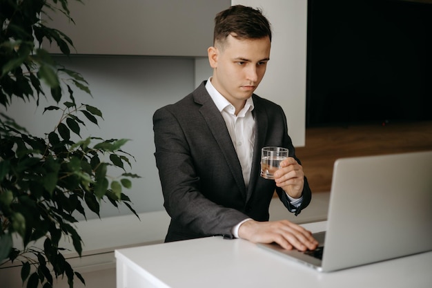 Geschäftsmann arbeitet an Laptop-Computer Geschäftsmann hält ein Glas Wasser im Büro