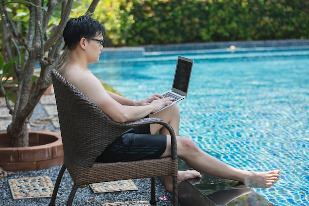 Geschäftsmann arbeitet mit Laptop am Schwimmbad
