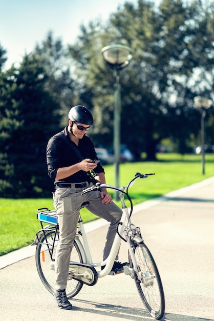 Geschäftsmann auf elektrischem Fahrrad, das auf Handy tippt