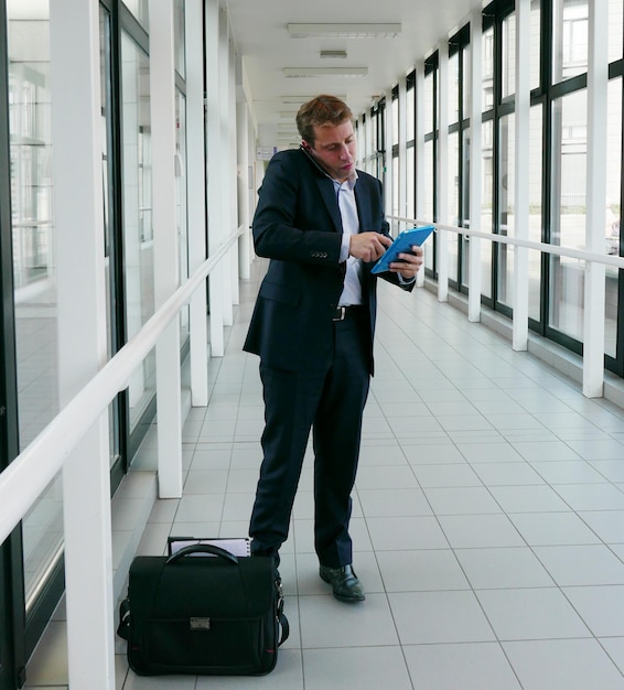 Foto geschäftsmann benutzt ein digitales tablet, während er im korridor des gebäudes steht