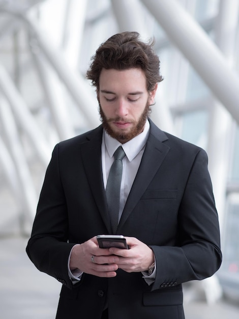 Geschäftsmann benutzt ein Handy, während er im Gebäude steht