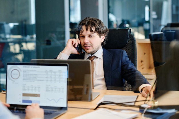 Geschäftsmann, der am Arbeitsplatz am Handy spricht