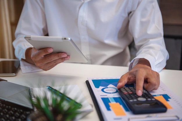 Geschäftsmann, der am Rechner arbeitet, um Finanzdatenbericht, Buchhaltungsdokument und Laptop-Computer im Büro zu berechnen, Geschäftskonzept.