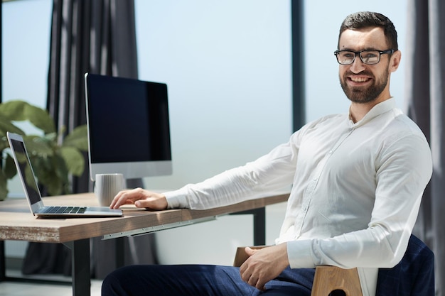 Geschäftsmann, der am Schreibtisch arbeitet an Laptop-Computer sitzt